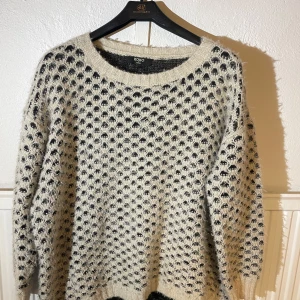 Stickad svartvit tröja från Koko - Säljer en stickad tröja från Koko i svart och vitt med coolt prickigt mönster. Tröjan har rund halsringning och långa ärmar. Den är fluffig och mjuk, perfekt för kyliga dagar. Oversized fit för en avslappnad vibe.