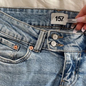 Lägmidjade Bootcut jeans från 157 - Ljusblå bootcut jeans från 157 med låg midja och snygg broderad detalj på bakfickorna. Jeansen har dubbla knappar framtill och klassisk femficksdesign. Använt väldigt fåtal gånger och säljer då dem är för korta för mig💕 