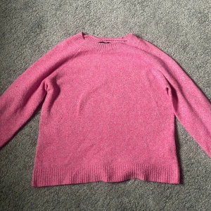 Rosa stickad tröja från Vero Moda - Superfin rosa stickad tröja från Vero Moda i storlek S. Tröjan har en klassisk rund halsringning, långa ärmar och ribbade muddar vid ärmslut och nederkant. Perfekt att slänga på sig när det är lite kyligare ute!