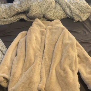 Beige teddyjacka/kappa från H&M Divided - Supermjuk och fluffig teddyjacka/kappa i beige från H&M Divided. Jackan har en oversized passform, hög krage och långa ärmar. Perfekt för att hålla sig varm och se chill ut under hösten och vintern. Den passar både M och L (kanske behöva tvättas, om man vill) 