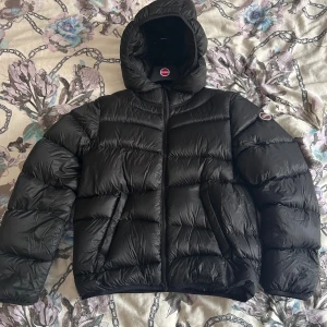Svart pufferjacka från Colmar - Säljer en svart pufferjacka från Colmar med huva och dragkedja. Jackan är lite använd men inga defekter. Kvitto finns ifall man vill ha, Nypris 5200kr