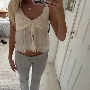 Söt spetslinnetopp i offwhite - Supersöt offwhite linnetopp med stickad överdel och transparent, broderad spets nertill. Toppen har v-ringning, breda axelband och knyt framtill. Perfekt för en romantisk look och passar till både jeans och kjol.