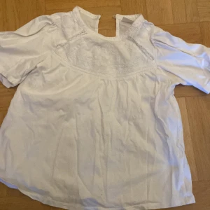 Vit broderad blus från Zara - Säljer en söt vit blus från Zara i storlek 152. Blusen har fina broderade detaljer och spetsinslag upptill, rund halsringning och korta ärmar. ❤️