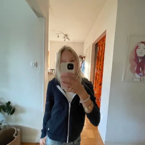 Mörkblå  hoodie med dragkedja - Säljer en mörkblå hoodie med vit dragkedja och huva. 