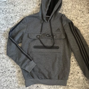 Grå hoodie från Adidas med svarta detaljer - Adidas Hoodie – Grå 👕 Storlek: S 🌫️ Färg: Grå ✨ Skick: 9/10 – sparsamt använd, mycket fint skick 💎 Märke: Adidas