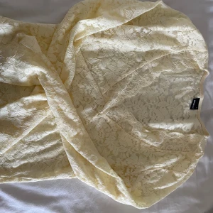 Ljusgul spetströja från Gina Tricot - Superfin ljusgul tröja från Gina Tricot i spets med blommigt mönster. Tröjan har omlott-detalj och är perfekt för sommarens alla tillfällen. Tunn och luftig med v-ringad halsringning. Aldrig använt.