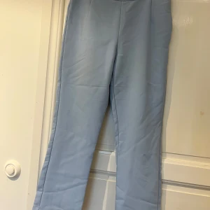 Ljusblå kostymbyxor från BikBok - Snygga ljusblå kostymbyxor från BikBok. Byxorna har en rak passform, hög midja och dold dragkedja i sidan. Perfekta för en clean och stilren look. Materialet känns mjukt och har en lätt stretch. Står stl 38 men extremt små i storlek, jag brukar ha 36-38 men får inte ens på mig dom längre, så mer som 32-34/xs?