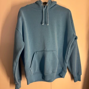 Blå hoodie - Blå hoodie med huva och snörning, samt en stor magficka framtill från BikBok. 