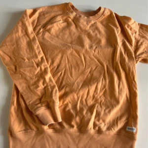 Orange sweatshirt från lager157 - En enkel och snygg orange sweatshirt från lager157. Tröjan har rund hals, ribbade muddar vid ärmslut och nederkant samt en liten etikett nertill. Perfekt för chill dagar och passar till det mesta.