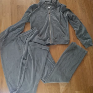 Grönt mjukis sätt från Gina Tricot - Mjuk och skönt mjukis sätt från Gina Tricot med hoodie och byxa. Hoodien har dragkedja och huva, byxan har resår i midjan och bakfickor. Perfekt för chill dagar eller när du vill vara extra comfy.