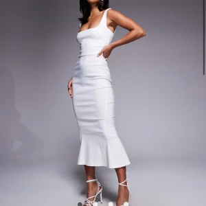 Vit figurnära långklänning - Supersnygg vit långklänning med breda axelband och fyrkantig urringning. Klänningen är figurnära med utsvängd nederdel och har en stilren, minimalistisk look. Perfekt för dig som vill sticka ut med en clean och elegant stil. Storlek XS men passa mig som har S eftersom den är stretchig. Endast haft på mig den på studenten och den är nu tvättad och helt fläckfri. Ingen champagne eller så har kommit i närheten av klänningen. Nypris 879kr