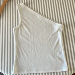 Vit oneshoulder topp från Stories L - Säljer en vit ribbad oneshoulder topp från Stories i storlek L. 