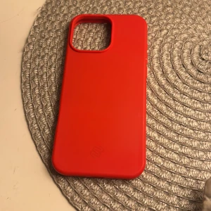 Röd mobilskal för iPhone, gummi material  - Snyggt röd mobilskal i silikon med stor kamerautskärning, passar iPhone-modeller med större kameralins. Skalet är i gott skick utan synligt slitage och ger bra skydd mot repor och stötar.