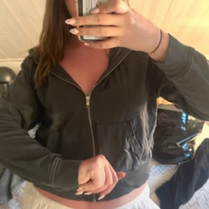 Grå hoodie med dragkedja - Mysig grå hoodie från BikBok i storlek L. Tröjan har huva med snörning, dragkedja framtill och två stora fickor. Perfekt för chill dagar eller när du vill ha en enkel och stilren look.