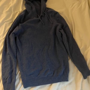 Blå stickad hoodie med huva - Mysig blå stickad hoodie med huva och snörning. 