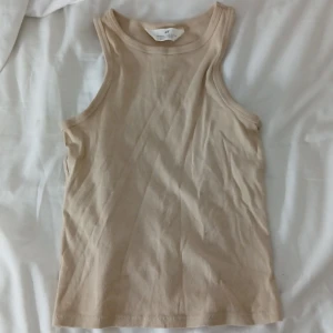 Beige ribbad linnetopp från H&M - Säljer en beige ribbad linnetopp från H&M i storlek 158/164. Toppen har ärmlös design med rund hals och är gjord i mjuk bomull. Perfekt för dig som gillar enkla och stilrena plagg med skön passform.🩷