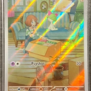 Ralts Pokémonkort - Upptäck en glittrande Pokémon-samlarbok med färgstarka illustrationer! Perfekt för dig som älskar Pokémon och vill ha en unik och cool samlarpryl. Boken har ett holografiskt omslag och visar en mysig scen med en Pokémon och dess tränare.