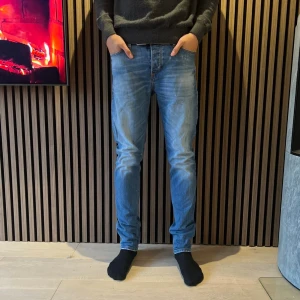 Blå jeans från Blue de Genes, slim fit - Snygga ljusblå jeans från Blue de Genes med klassisk femficksdesign och bruna sömmar. Modellen har slim passform och normal midja, med läderpatch bak och diskret logodetalj vid fickan. Perfekta för dig som gillar stilrena och bekväma jeans. Storlek 33/34 men passar W30
