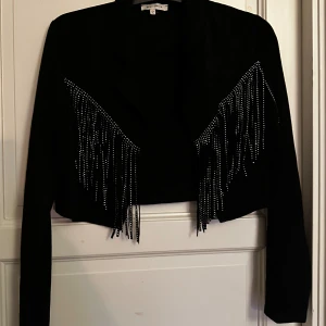 Svart mockajacka med fransar - Snygg svart mockajacka från Missguided med långa ärmar och croppad passform. Jackan har coola fransdetaljer 