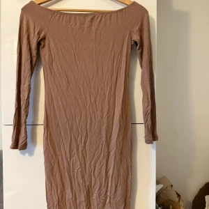 Beige långärmad klänning från SHEIN - En enkel och stilren beige långärmad klänning från SHEIN i mjuk bomullsblandning med stretch. Klänningen har en kroppsnära passform och offshoulder-ringning som ger en snygg siluett. Perfekt för dig som gillar minimalistisk stil.