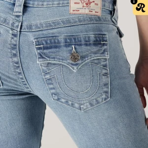Ljusblå jeans från True Religion - Säljer ett par ljusblå jeans från True Religion med ikonisk bakficka och tydliga kontrastsömmar. Jeansen har klassisk femficksdesign, knappstängning och är tillverkade i mjukt denimtyg. Perfekta för dig som gillar streetwear och vill sticka ut.