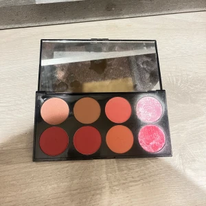 Revolution Ultra Blush Palette - Säljer en Revolution Ultra Blush Palette med åtta olika nyanser av rouge i både matta och skimrande toner. Färgerna går i rosa, persika, korall och rött. Paletten har en stor spegel och är perfekt för att skapa olika looks.