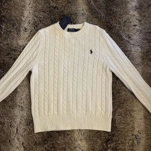 Polo Ralph Lauren stickad vit - Vit kabelstickad tröja från Polo Ralph Lauren som är perfekt för daglig kofta, tröjan är i S storlek och är i utmärkt skick 8/10 och medföljer Polo taggen. Pris kan diskuteras och om du har intresse eller frågor, är bara kontakta mig🤝