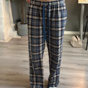 Blårutiga mjukisbyxor  - Rutiga mjukisbyxor med elastisk midja och blå snörning. Byxorna har ett avslappnat, loose fit och mjukt material. 