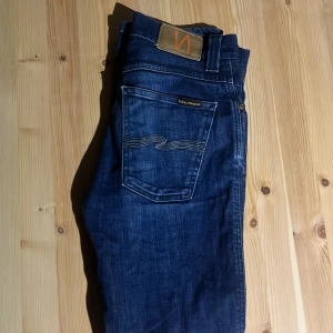 Blå jeans från Nudie Jeans Co W29 L30 - Snygga blå jeans från Nudie Jeans Co med klassisk femficksdesign och ikonisk broderad bakficka. 