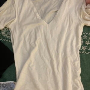 Vit v-ringad t-shirt - En enkel vit t-shirt med v-ringning och korta ärmar. Perfekt basplagg som funkar till det mesta och är lätt att matcha med andra kläder. Gjord i mjukt material för en bekväm känsla.