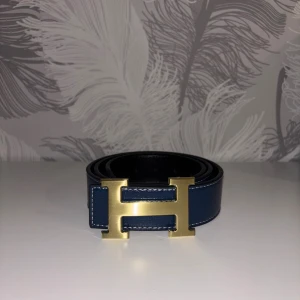 Mörkblå H bälte - Fin mörkblå bälte som är helt ny. Den är 110cm lång. Och med bältet så får du ett litet metall verktyg som kan göra extra hål på bältet med hjälp av hammare. Tveka inte att dm:a vid frågor eller intresse!!