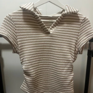 Randig stickad topp med krage (pris kan diskuteras) ❤️❤️ - Säljer en beige och vit stickad topp med korta ärmar och krage. Toppen har ett randigt mönster och är gjord i ett grovt stickat material som ger en cool textur. Perfekt för dig som gillar retrovibbar och vill ha något unikt i garderoben.