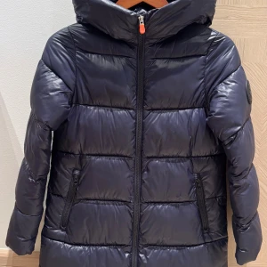Save the Duck dunjacka - Mörkblå vadderad jacka/kappa. Storlek 12 år. Nypris 3000 kr. Två små rispor. Se bild. Mer info:  https://www.zalando.se/save-the-duck-millie-vinterkappa-rock-blue-black-td023r012-k