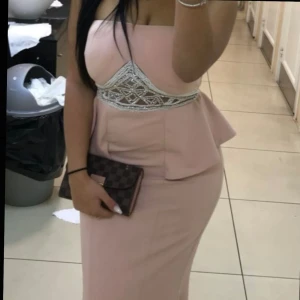 Ljusrosa axelbandslös långklänning - Säljer en elegant ljusrosa axelbandslös långklänning med snygg peplumdetalj vid midjan och dekorativt broderi med pärlor. Klänningen har figurnära passform och är perfekt för dig som vill sticka ut med en feminin och stilren look. Behöva tvättas därav billiga priset!