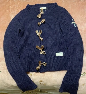 Mörkblå kofta från Odd Molly med rosetter i storlek 0 - Superfin mörkblå stickad kofta från Odd Molly med snygga satinrosetter som knäppning framtill. Det är storlek 0, motsvarande XS. Den är i väldigt bra skick!