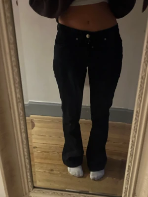 Svarta bootcut jeans - Säljer ett par svarta jeans med bootcut passform. Byxorna har låg midja, klassiska fem fickor och bälteshällor. Storlek 36/S, Innerbenslängd- 81, från Karen Millen! 