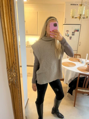 Beige/brun stickad väst med polokrage - Säljer en beige/brun stickad väst med polokrage och snygg snörning i sidorna. Västen har en loose passform och är ribbad i strukturen. Perfekt att slänga över en långärmad tröja för extra lager. Storlek S/M