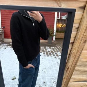 Svart tröja med half zip - Svart långärmad tröja med half zip i halsen, perfekt för kyliga dagar. Enkel och stilren design som funkar till jeans eller andra favoritplagg. Tröjan har en normal passform och är riktigt skön att bära.