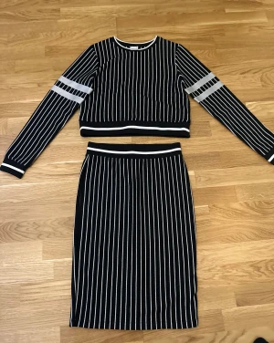 Set / Svartvit randig kjol och tröja från Gina Tricot - Säljer en svartvit randig kjol från Gina Tricot och topp. Kjolen är i storlek S, tröjan XS. Kjolen är midilång med smala vertikala ränder och har en elastisk midja med vit kant. Materialet är mjukt och stretchigt, perfekt för en chill och snygg look.