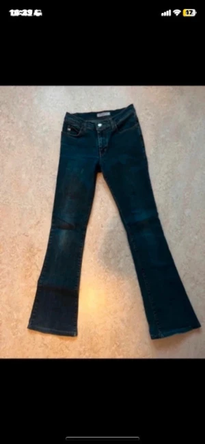 Bootcut jeans från Miss Sixty - Snygga blå bootcut jeans från Miss Sixty med klassisk femficksdesign och låg midja. Jeansen har en mörk tvätt, tydliga sömmar och logotyp på bakfickan. Perfekt för dig som gillar retrovibbar och vill ha ett par jeans med riktigt schysst passform.