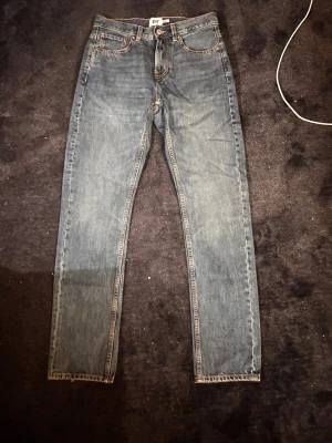 Levi's 501 blå jeans straight fit - Klassiska Levi's 501 jeans i blå denim med raka ben och normal passform. Jeansen har fem fickor, knappgylf och tydliga sömmar. Perfekta för dig som gillar en tidlös och avslappnad stil.