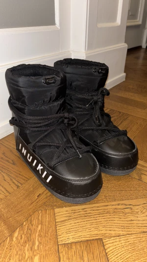 Svarta Inuikii  - Säljer ett par svarta Inuikii som är formen som moon boots med hög skaft och tydlig logga på sidan. Använda max 2 gånger om ens det! 
