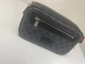 Gucciväska  - Säljer min stilrena midjeväska i GG-canvas med svarta detaljer. Väskan är i bra skick och har använts sparsamt. 700kr först till kvarn.