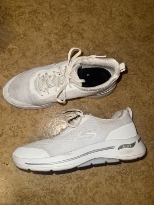 Vita Skechers Arch Fit sneakers - Säljer ett par vita Skechers Arch Fit sneakers med  hålfotsinlägg i, original sula finns inte i skorna.