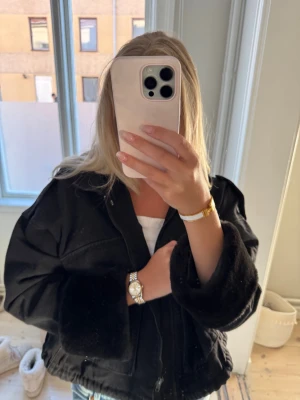 Svart jacka med päls  - Säljer en svart jacka med fluffiga muddar och snörning i nederkant. Jackan har dragkedja framtill, stora fickor och en loose passform. Perfekt för dig som gillar en chill och trendig look. Jackan är långärmad och har en cool, oversized vibe.
