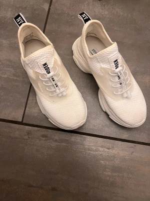 Vita sneakers  - Vita sneakers från Steve Madden med stickad mesh-ovandel och platt sula. Skorna har snörning med elastiska band