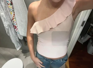 Ljusrosa oneshoulder topp med volang - Säljer en ljusrosa oneshoulder topp med bred volang längs halsringningen. Toppen är tight och ärmlös med en snygg asymmetrisk skärning. Materialet känns mjukt och stretchigt