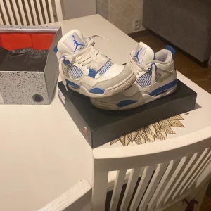 Nike Air Jordan 4 Retro Vit/Blå - Nike Air Jordan 4 Retro sneakers i vit och blå färg med meshpaneler och klassisk snörning. Skorna har en platt sula med synlig Air-enhet och detaljer i blått på häl, tunga och sidor. Ikonisk Jumpman-logga på tungan och bak. Perfekt för dig som gillar streetwear och sneakers. Man kan använda skorna till alla Årstider också det är de som är unika med dessa skor! Skulle verkligen rekommendera att köpa dessa! Köpta för 4600 Säljer för 1900 väldigt bra pris för skor som har varit använda 2 gånger!