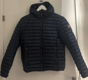 Colmar jacka - Mörkblå dunjacka från Colmar med huva och två sidofickor med dragkedja. Jackan har ett quiltat mönster och Colmar-logga på ärmen. Perfekt till vintern och kalla dagar. Har en snygg, sportig look med normal passform. Sitter som ny, knappt använd. Pris ej diskuterbart, hör av dig vid funderingar 🤙 