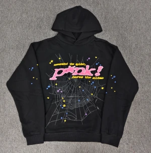 Svart Pink! Hoodie från Sp5der - Cool svart hoodie från Sp5der med stor huva och tryck på bröstet. Framsidan har ett spindelnätsmotiv, färgglada stjärnor och text i rosa med vita prickar. Baksidan har en gul stjärna med S-logga. Mjuk bomullskvalitet och ribbade muddar. KOM MED BUD!
